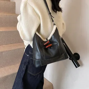 Chic black hobo bag with white faux shearling trim and decorative wooden horn toggles