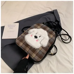 Detail of checkered tote bag with a 3D plush puppy character and adjustable black strap