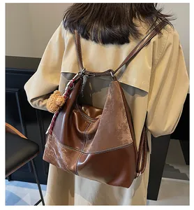 Detail of vintage brown tote bag with white contrast stitching and plush bear charm
