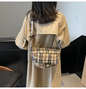 Detail of checkered quilted crossbody bag with vintage metal turn-lock and brown plaid fabric