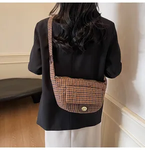 Detail of vintage plaid crossbody bag with a golden twist lock on a curved flap pocket