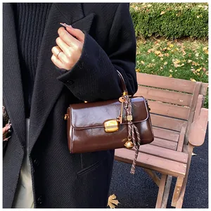 Detailed view of vintage dark brown underarm bag featuring a golden buckle and charms