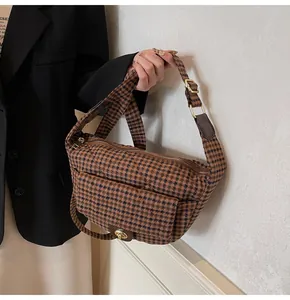 Detail of retro houndstooth crescent bag with wide strap and gold metal hardware