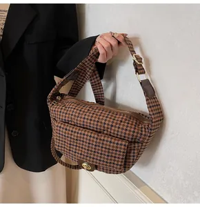 Close-up of brown plaid waist bag with metal turn-lock and adjustable fabric strap
