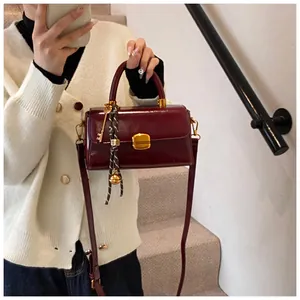 Close-up of wine red glossy mini bag with metal clasp and decorative charms on stairs