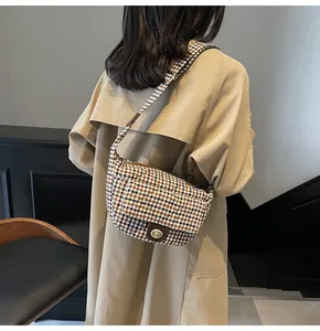 Close-up of vintage brown plaid crossbody bag with gold buckle on trench coat model