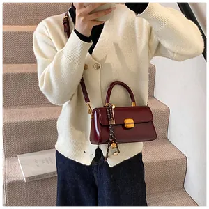 Detail of burgundy patent leather bag with gold buckle and silk scarf handle accent