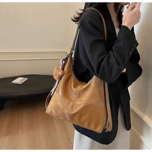 Detail of vintage brown leather tote bag with contrast stitching and bear charm accessory