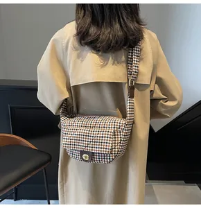 Detail of vintage plaid crossbody bag with metal twist lock worn with a khaki trench coat