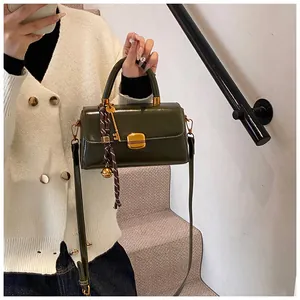 Detail of dark green glossy leather bag featuring gold hardware and elegant tassel charm