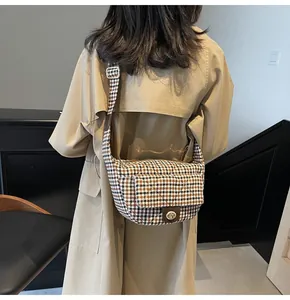 Detail of checkered crossbody bag with golden metal rotating buckle and wide strap
