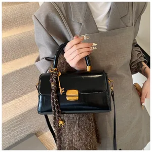 Detail of black glossy handbag featuring gold hardware and a creative key charm