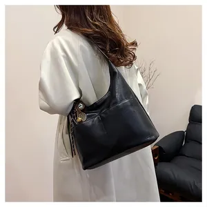 Détail du sac hobo en similicuir noir avec surpiqûres et breloque raquette de tennis