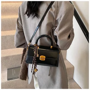 Close-up of black glossy leather bag with gold hardware and silk scarf on handle