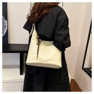 Détail d'un cabas crème avec pampille rayée et boucle métallique sur un manteau noir