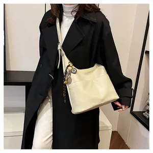 Détail d'un sac cabas crème en cuir PU texturé avec un pendentif de raquette de badminton