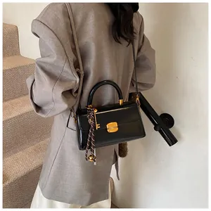 Detail of black mirror leather bag with gold buckle and silk scarf on the handle