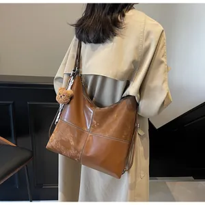 Detail of vintage brown patchwork tote bag with cute plush bear charm on beige trench coat