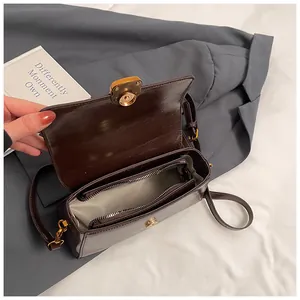 Close-up of dark brown glossy leather bag with gold buckle and internal zip compartment