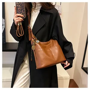 Détail d'un sac hobo en cuir caramel avec pendentif raquette et bandoulière réglable