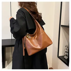 Détails du sac hobo en cuir caramel avec des breloques en métal et texture riche