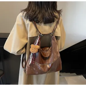 Detail of vintage brown tote bag with white contrast stitching and plush bear charm