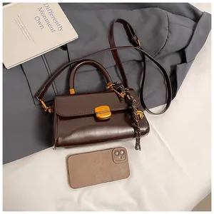 Detail of vintage coffee leather crossbody bag with gold hardware and phone size reference