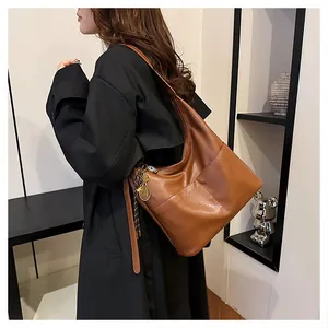 Détail du grand sac cabas marron foncé avec texture litchi et pendentif sur modèle