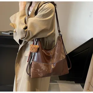Detail of vintage brown tote bag with contrast stitching and cute plush bear charm
