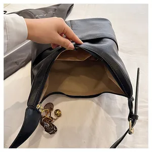 Détail de l'intérieur d'un cabas noir avec doublure beige et breloque de tennis