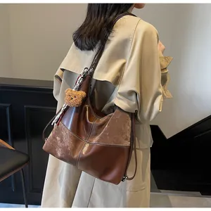 Close-up of vintage brown tote bag featuring contrast stitching and plush bear charm