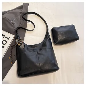 Détail du sac cabas en similicuir noir avec pochette assortie et breloque raquette de tennis