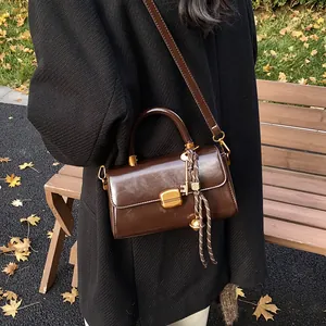 Vintage chocolate brown leather shoulder bag with gold square lock and woven keychain