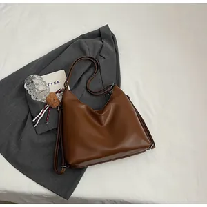Close-up of vintage brown leather tote bag with soft texture and cute plush bear charm