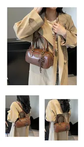 Detail of vintage brown leather Boston bag with gold logo and woven pendant charm