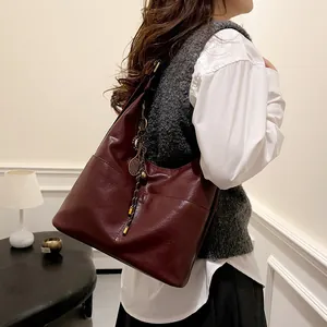 Grand sac cabas bordeaux en cuir souple avec breloque raquette de tennis et pompon élégant