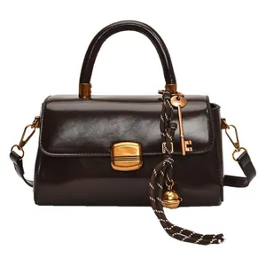 Glossy dark brown rectangle crossbody bag with gold hardware and top handle detail