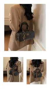 Detail view of black retro pillow bag with golden hardware and tassel pendant charms