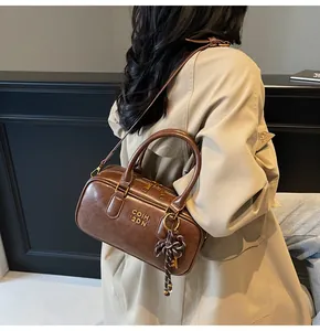 Close-up of vintage dark brown Boston bag with smooth leather texture and bow charm