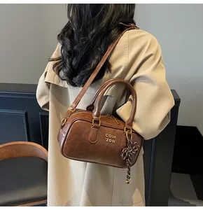 Close-up of vintage brown Boston bag featuring golden lettering and stylish striped knot charm