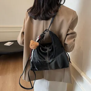 Vintage black hobo tote bag with white contrast stitching and a plush bear charm