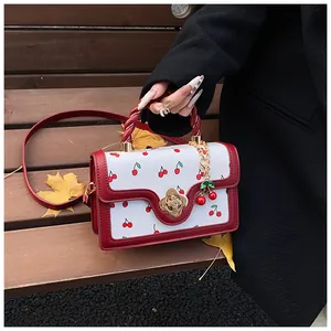Close-up of cherry print crossbody bag with gold clover lock and 3D cherry charm