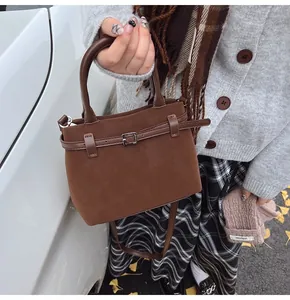 Close-up of a mini dark brown frosted leather bucket bag with silver buckle and crossbody strap