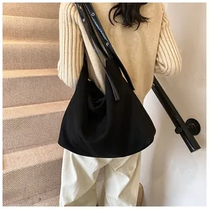 Close-up of large black suede hobo bag with eyelet leather strap on beige stairs