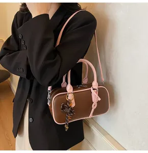 Detail of a brown and pink bowling bag showing its texture, color contrast and charms