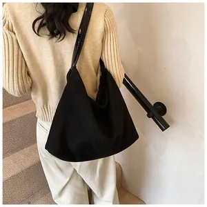 Detailed view of a black suede tote bag with shiny shoulder straps for daily commute