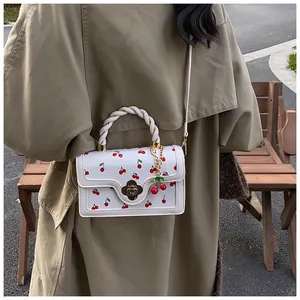 Detail of white leather handbag with red cherry print and floral metal clasp clasp