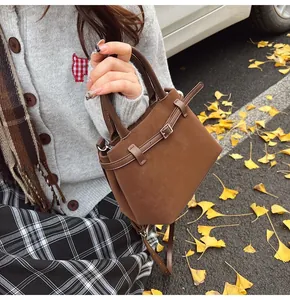 Close-up of deep brown matte leather tote bag with silver buckle in autumn setting