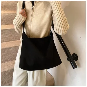 Close-up of black matte suede tote bag worn over the shoulder with minimalist texture