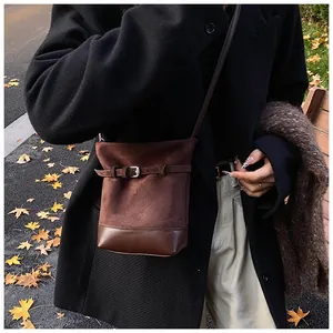 Détail du sac seau en daim marron et cuir avec boucle sur fond de rue d'automne
